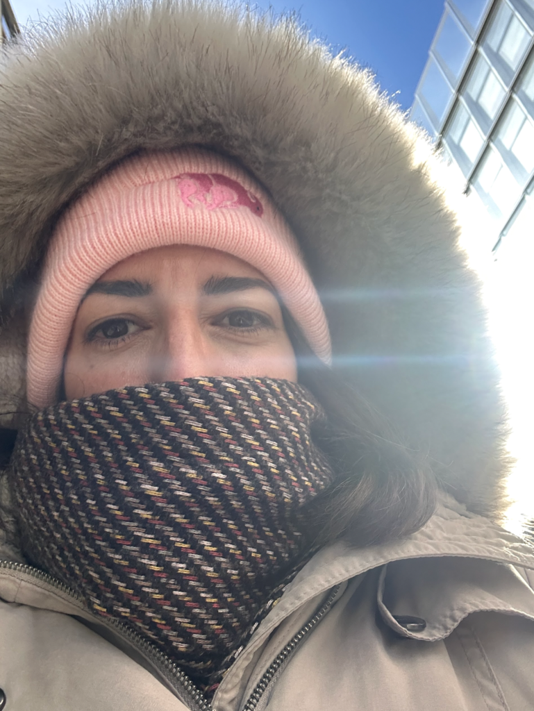 Vanessa's eyes peer out from under a thick beanie, furry hood, and warm scarf. 