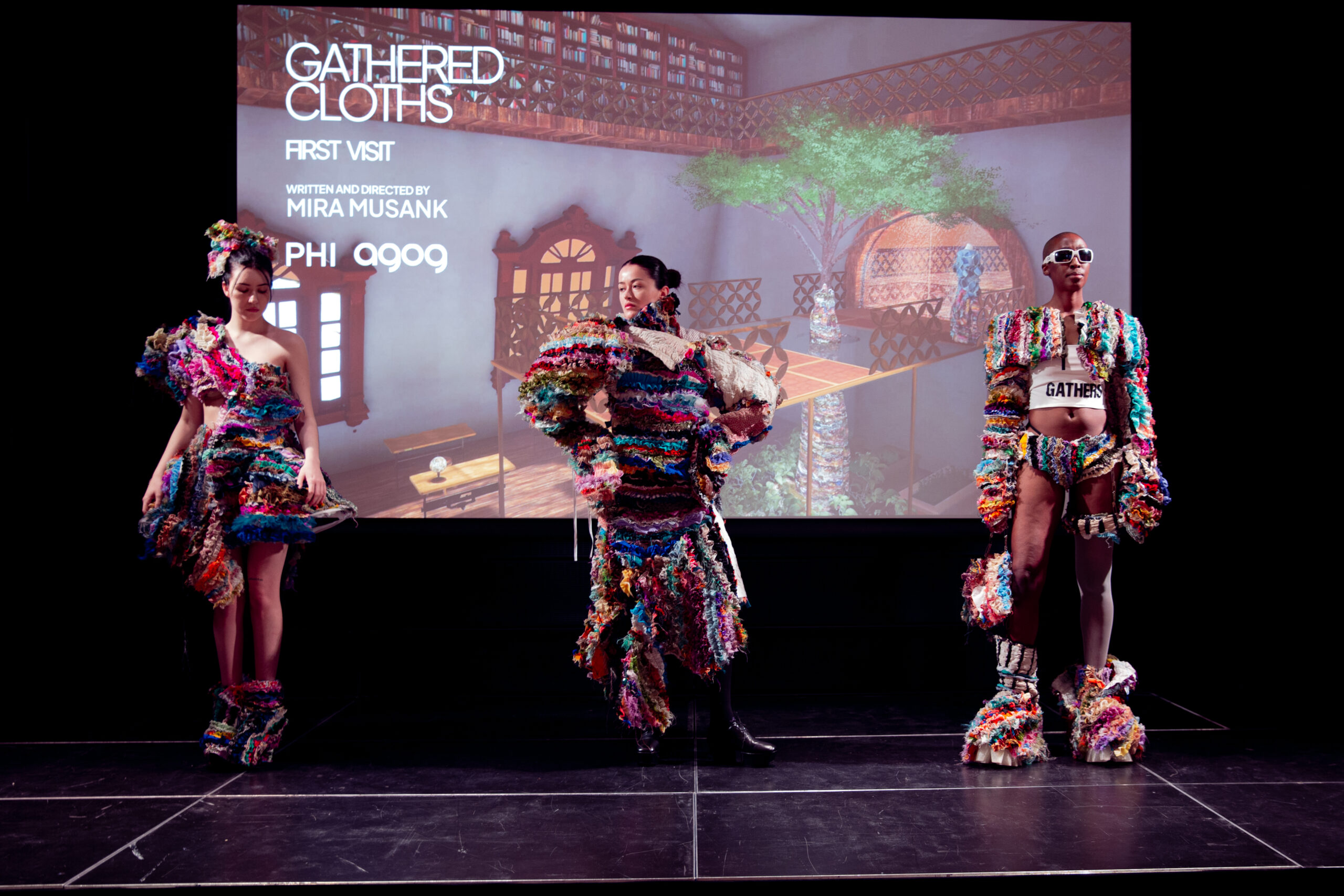 Three live models don gathered cloths ruffled fabric garments on stage at the end-of-residency show.